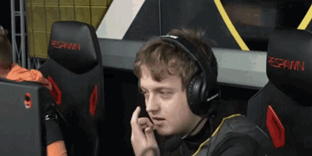 a man wearing headphones sits in a chair that says spawn on it