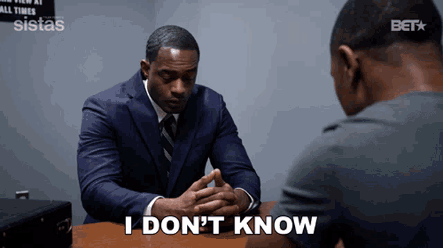 a man in a suit and tie sits at a table with another man and says i don t know