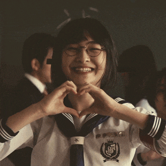 a girl in a school uniform making a heart shape