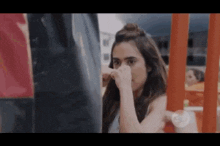 a woman is standing in front of a punching bag and covering her face .