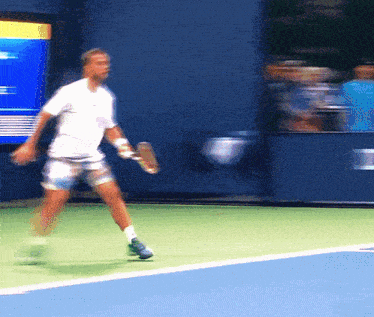 a blurry picture of a man playing tennis on a blue court
