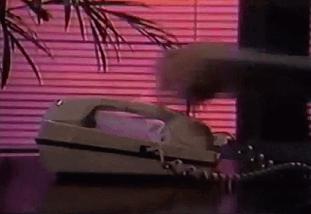a telephone is on a table in front of a window with blinds .