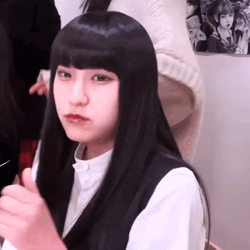 a girl with long black hair is wearing a white shirt and black vest