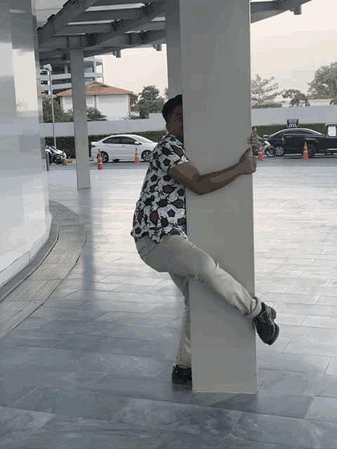 a man leans against a white pillar in a parking lot with a sign that says ' a ' on it