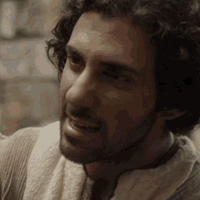 a man with curly hair and a beard is wearing a white robe