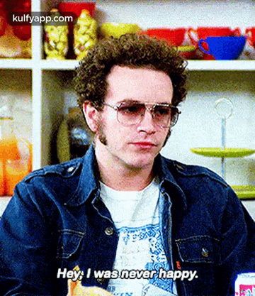 a man wearing sunglasses and a denim jacket is sitting at a table and saying hey i was never happy .