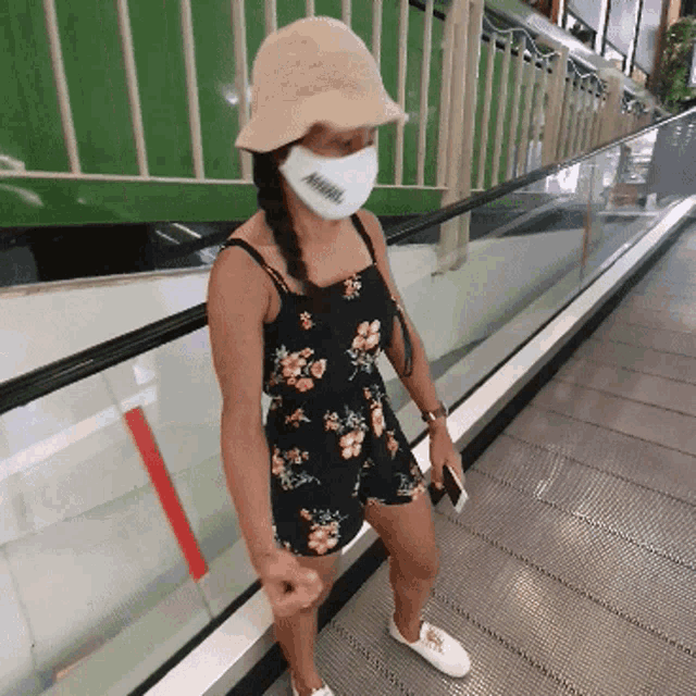 a woman wearing a floral dress and a white face mask with the word miami on it