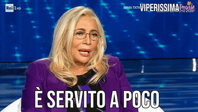 a woman in a purple jacket and glasses says e servito a poco