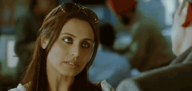 a close up of a woman wearing sunglasses looking at a man .