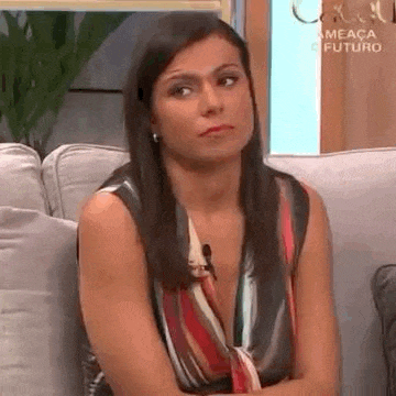 a woman is sitting on a couch with her arms crossed making a funny face .