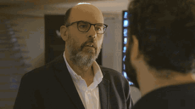 a man with glasses and a beard looks at his reflection