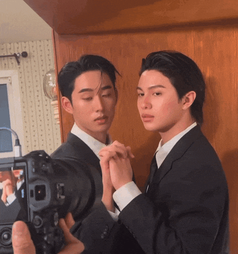 a man taking a picture of two men in suits with a canon camera
