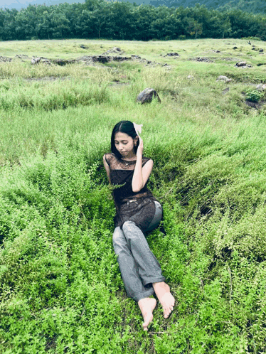 a woman is laying in a field of tall grass