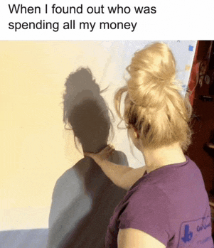 a woman in a purple shirt looks at her shadow on a wall