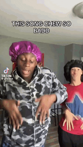 a man wearing a purple bonnet is dancing with another man in a red shirt .