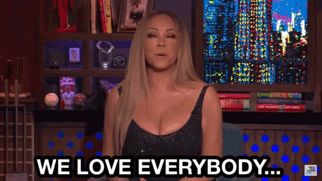 a woman says " we love everybody " in front of a bookshelf