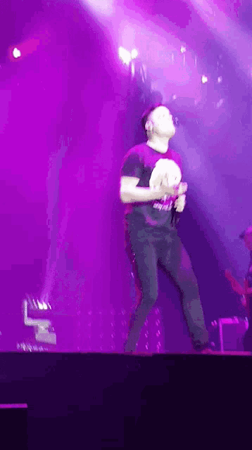 a man in a purple shirt is dancing on stage