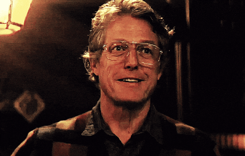 a man wearing glasses and a plaid shirt is smiling