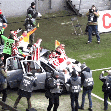 a group of soccer players are sitting in the back of a car with the word foto on their vests