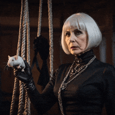 a woman in a black dress is holding a small white mouse