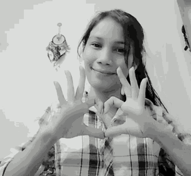 a girl in a plaid shirt makes a heart shape with her hands