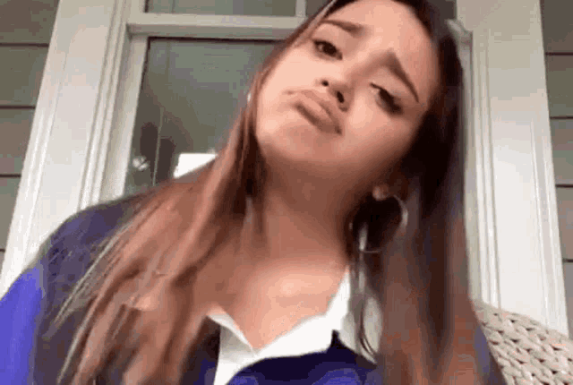 a woman is making a funny face while sitting on a chair in front of a window .