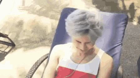 a woman in a red and white dress is sitting in a chair with her hair in a plastic bag .