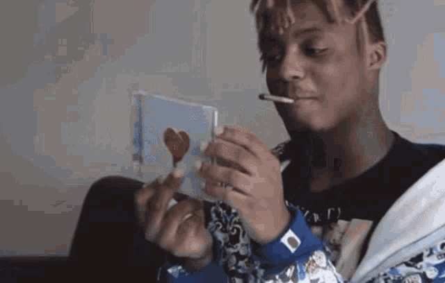 a young man is smoking a cigarette while looking at a cd .