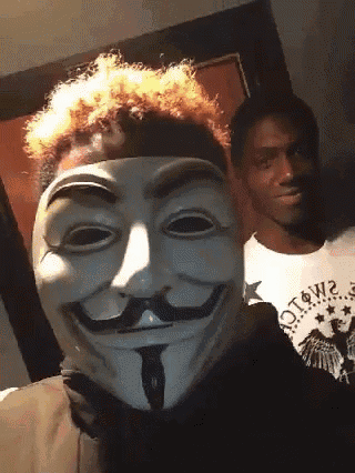 a man wearing a mask with a mustache is standing next to another man wearing a shirt that says otown