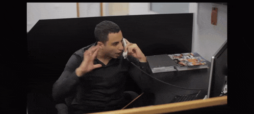 a man in a black shirt is talking on a telephone