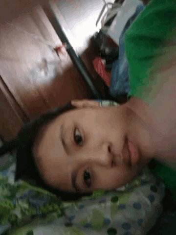 a woman in a green shirt is laying on a bed with her head on a pillow .