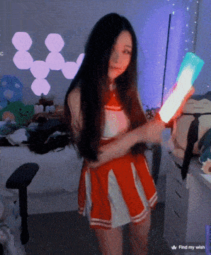 a woman in a cheerleader outfit is holding a light in front of a screen that says find my wish