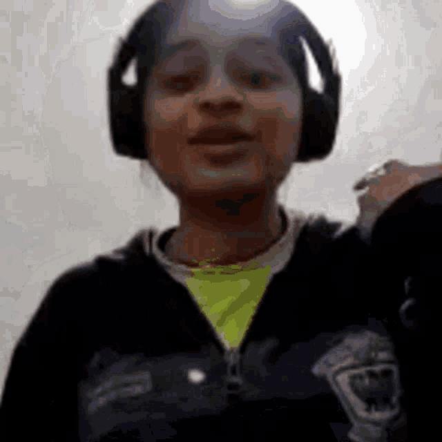 a young girl wearing headphones and a black jacket is smiling .