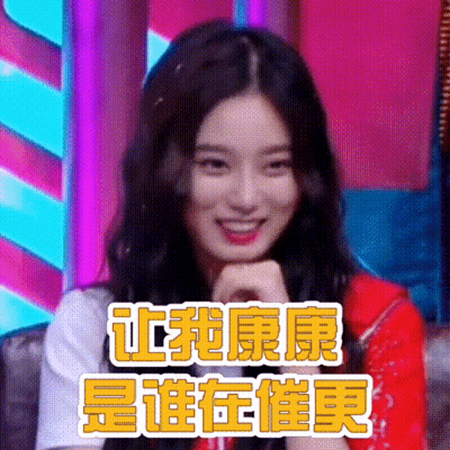 a woman is sitting on a couch with her hands on her chin and smiling in a foreign language .