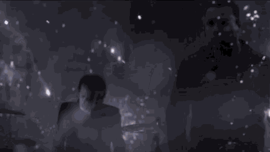 a group of people are standing in a dark room with smoke coming out of their eyes .