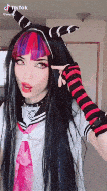 a girl with long black hair and red and blue hair is wearing a sailor suit and striped gloves .