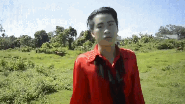 a man in a red shirt and black tie is standing in a grassy field