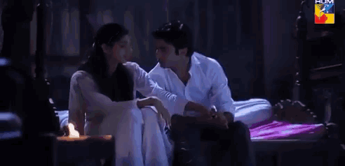 a man and a woman are sitting next to each other on a bed with hum written in the corner