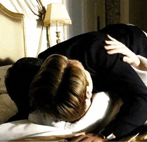 a man in a suit is laying on a bed with another man