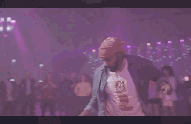 a man wearing a bandana is dancing in front of a crowd of people