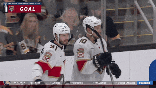 two hockey players celebrate a goal in front of a screen that says goal on it