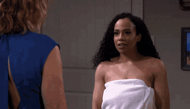 a woman wrapped in a towel stands next to another woman
