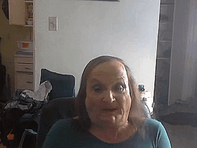 a woman in a green shirt is sitting in a chair and looking at the camera .