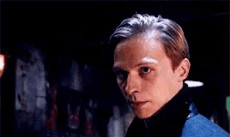 a young man in a blue sweater is looking at the camera .