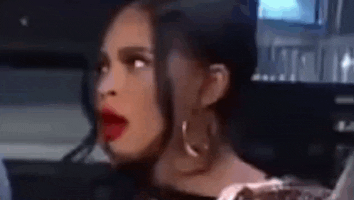 a woman is sitting in a car with her mouth open and a surprised look on her face .