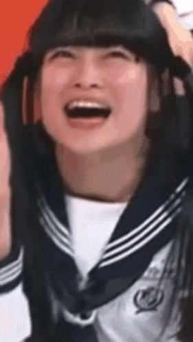 a girl in a sailor uniform is laughing and holding her hair