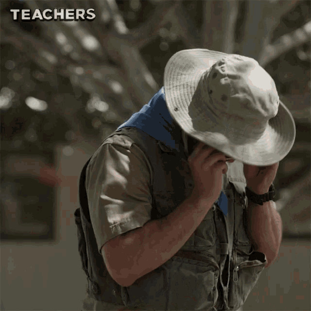 a man wearing a hat and a vest with the words teachers above him