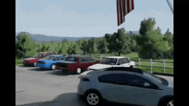 a row of cars are parked in a parking lot with a flag flying in the background .