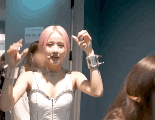 a woman with pink hair is standing in front of a sign that says kiss of lip