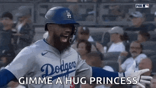 a baseball player in a dodgers uniform is giving a hug to a fan .